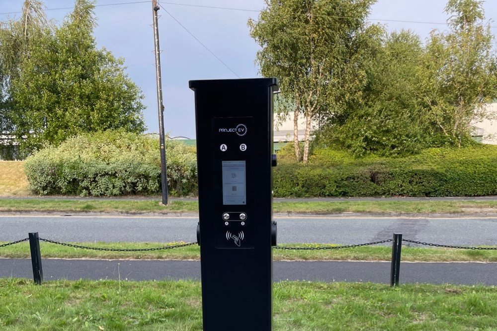 Ground-mounted EV charging pedestal with protective hoop