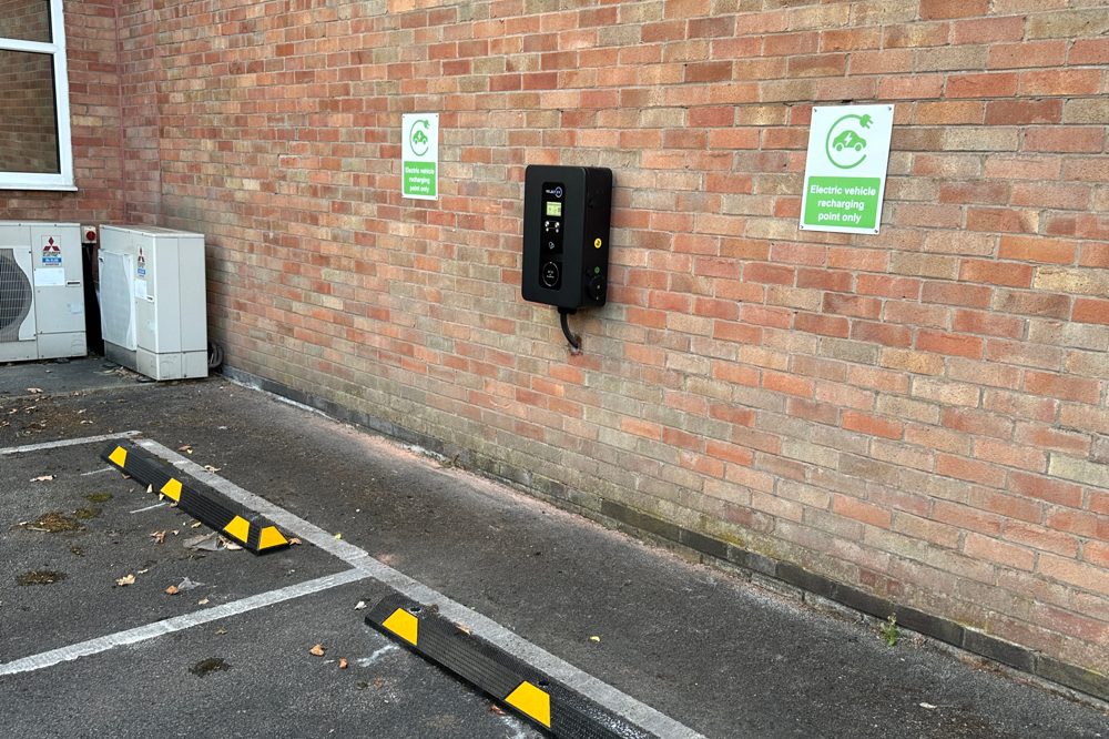 Wall-mounted EV charger serving a marked workplace charging bay