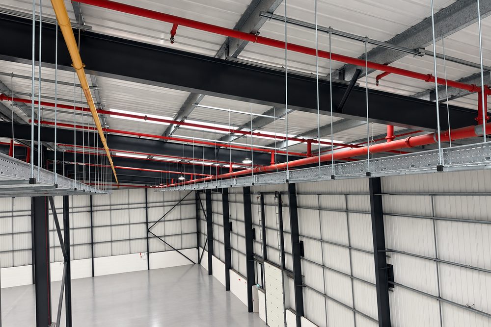 Cable tray installed alongside mechanical pipework in a new industrial unit